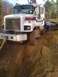 1992 Ford Bronco - A white cement truck is stuck in a muddy ditch, with a person standing near the driver's side door and a tow strap attached to the front.