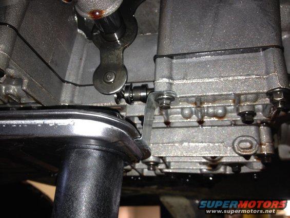 Transmission pan removed, showing filter and internal linkage. Some fluid drips visible