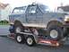 1992 Ford Bronco - A Ford Bronco is being loaded onto a U-Haul trailer, with two people attending to it from below.
