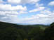 1992 Ford Bronco - A scenic view of rolling green mountains under a cloudy blue sky, with a website watermark visible.