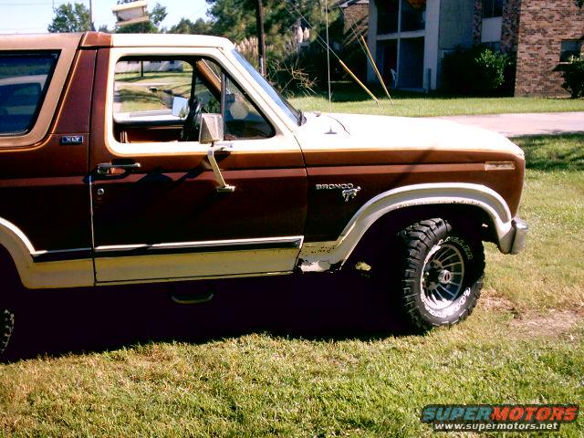 Brown and white 1980 Ford Bronco side view, showing a dented fender and off-road tires