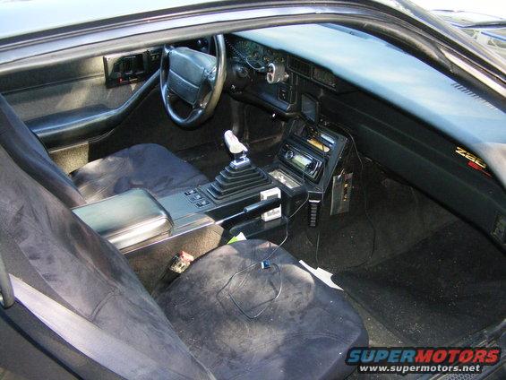 Interior view of a Z28 Camaro showing the dashboard, steering wheel, center console with manual shifter, and seats