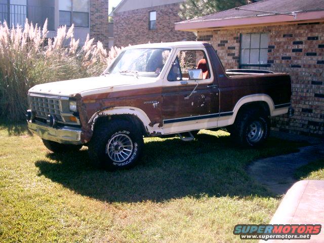 1980 Ford Bronco parked on grass next to a brick building