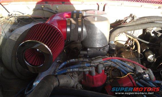 Engine bay with red cone air filter, silver air intake housing, and blue spark plug wires