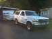 1992 Ford Bronco - A white 1992 Ford Bronco is parked next to a garage, hitched to a pop-up camper.