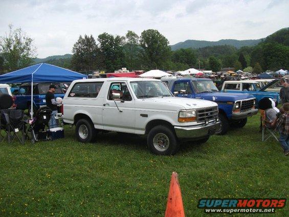 White 1992 Ford Bronco parked on grass, front 3/4 view, cloudy day
