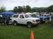 1992 Ford Bronco - A white 1992 Ford Bronco is parked on a grassy field with other vehicles and tents in the background.
