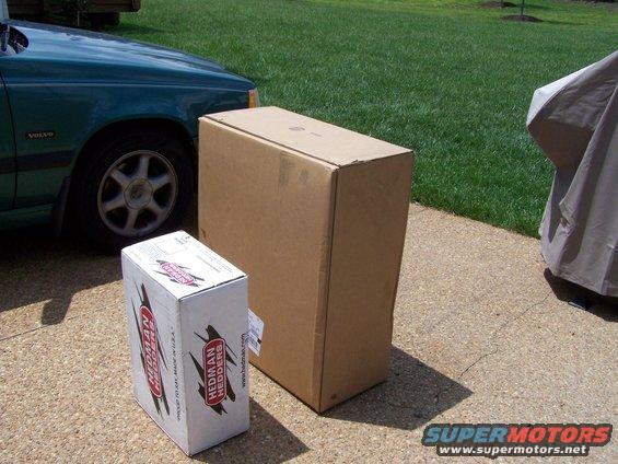 Green Volvo car side view with two cardboard boxes on a driveway