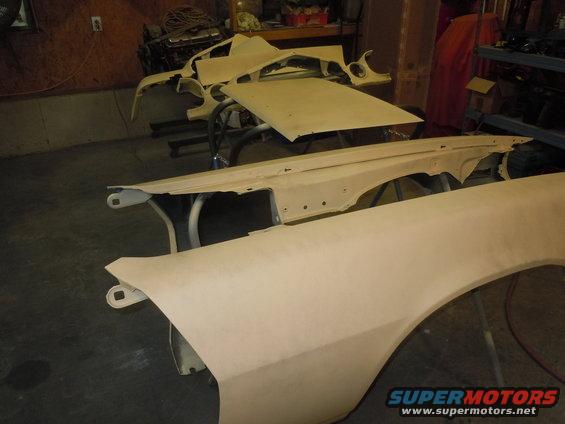 Car fenders and hood laid out in a workshop, possibly for restoration