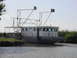 1993 Ford Bronco - A gray boat with a white superstructure is docked near a grassy bank under a clear sky.
