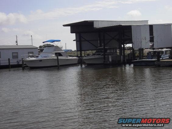 boats docked under covered slips at a marina with a small building nearby