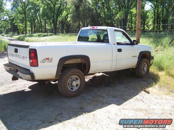 White Chevrolet pickup truck with 4x4 badging, parked on a dirt road