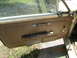 1968 Mercury Cougar - The interior door panel of a 1968 Mercury Cougar shows brown upholstery, a chrome handle, and a pull strap.