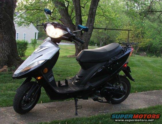 Black scooter with silver front panel parked on a sidewalk