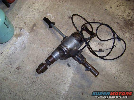 Heavy-duty electric drill with cord and handle, resting on concrete floor