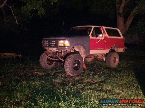 1987 Ford Bronco with front fenders painted different colors, lifted on jack stands