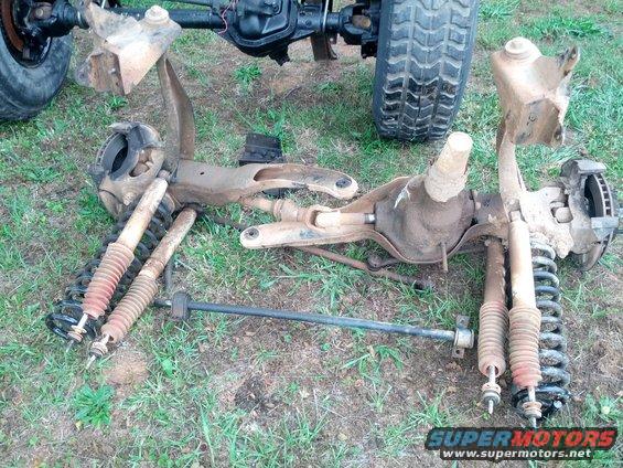 Front and rear axle assemblies with shocks and springs laid out on grass
