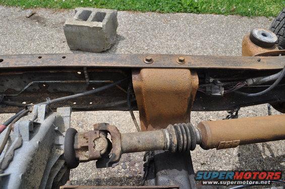 Rusty vehicle frame with driveshaft, U-joint, and differential visible