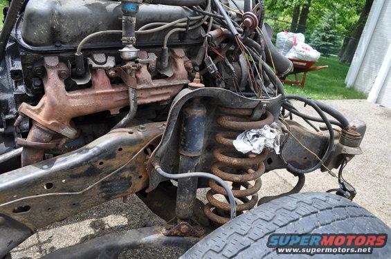 Engine block, exhaust manifold, and front suspension with coil spring and shock absorber. Some wiring is visible