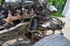 1986 Ford Bronco - Close-up view of rusty engine and suspension parts from a vehicle undergoing repair or awaiting repair.