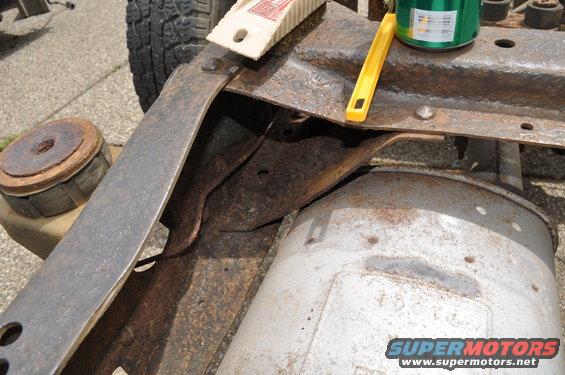 Close-up of rusty vehicle frame with exhaust pipe and a green can of paint
