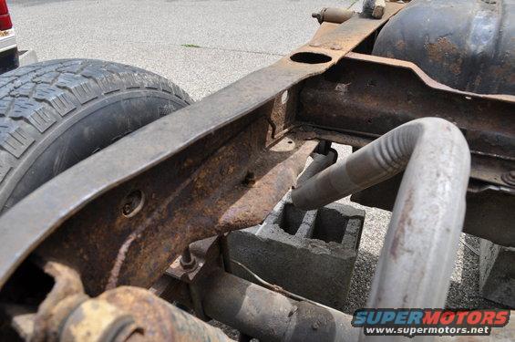 Rusty vehicle frame with exhaust pipe and tire, supported by cinder blocks