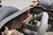 1986 Ford Bronco - Close-up view of a heavily rusted vehicle frame and exhaust system, with a tire visible on the left.