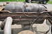 1986 Ford Bronco - The fuel tank and frame components are visible, with significant rust and fuel lines attached.