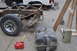 1986 Ford Bronco - A heavily rusted vehicle frame and suspension components are visible, alongside a detached fuel tank and a red gas can.