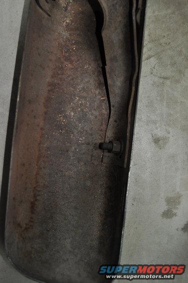 Rusted exhaust pipe with a crack and a bolt, showing significant corrosion