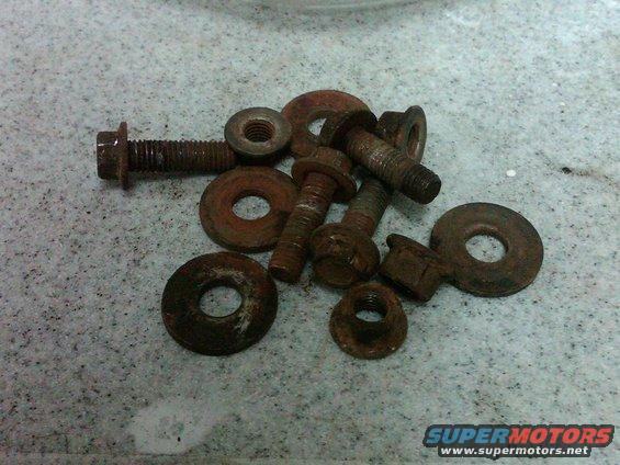 Pile of assorted rusty bolts and washers on a speckled surface