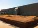 2012 Ford Bronco - An outdoor RC car track features dirt jumps and wooden borders in front of a large building.