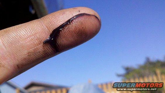 Finger with dark oil smudge against blue sky
