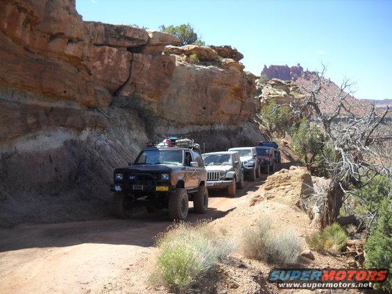 Black Ford Bronco II with off-road modifications driving on a dirt trail