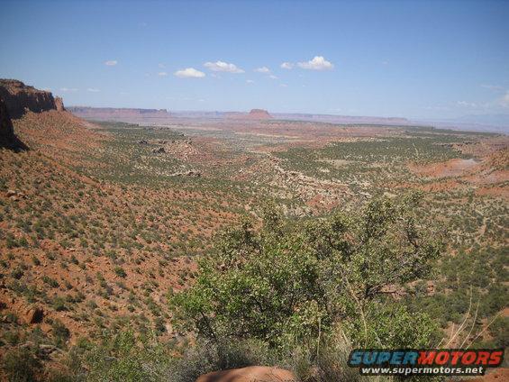 Desert landscape with mesas and sparse vegetation under a blue sky