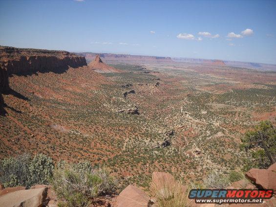 Desert landscape with mesas and sparse vegetation under a blue sky