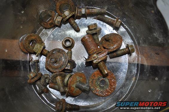 Pile of rusty bolts and washers in a clear container