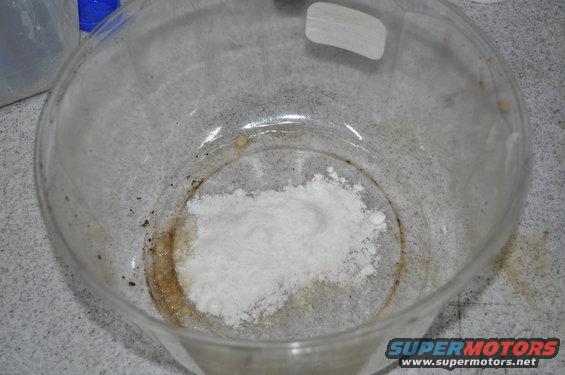 White powder in a clear glass dish with some brown residue around the edges