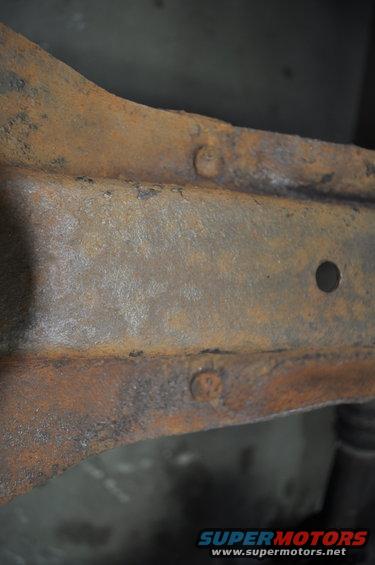 Rusted frame section with visible bolts and a hole