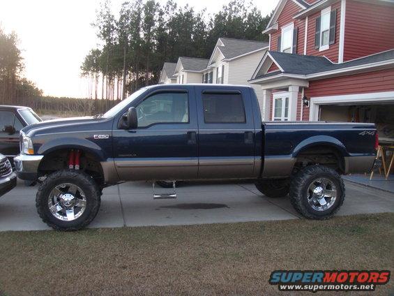 Lifted blue and tan Ford F-250 pickup truck parked in driveway