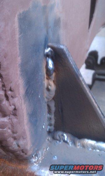 Close-up of a metal frame with visible welds. Supermotors.net logo at bottom