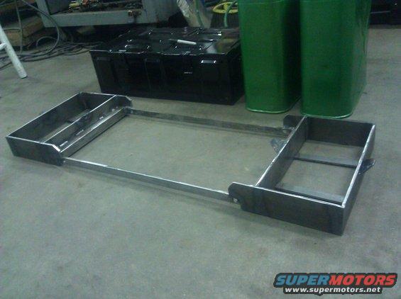 Custom metal frame with two rectangular boxes on either side, resting on a concrete floor