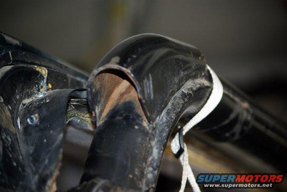 Close-up of a black metal roll bar joint with a white rope tied to it