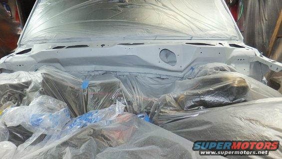 Engine bay covered in plastic sheeting for painting. Parts of the engine are visible under the plastic