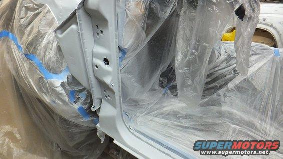 Car door jamb and interior covered in plastic sheeting and blue tape for painting