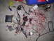 2003 Hyundai Tiburon - A complex and tangled vehicle wiring harness, including an ECU and relays, lies spread out on a concrete floor.