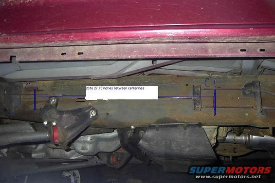 Undercarriage of a red vehicle showing a rusty frame with blue centerlines and a measurement of 26 to 27.75 inches