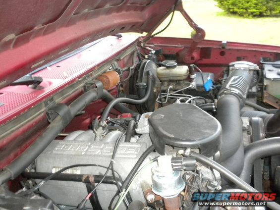 Red 1994 Ford Bronco engine bay with visible V8 engine components and Supermotors.net watermark
