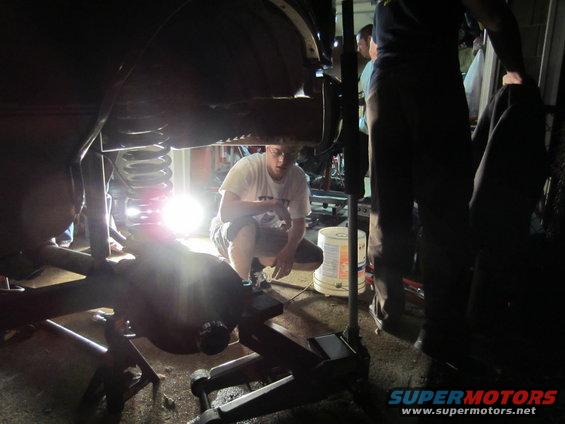 guy working on vehicle suspension, jacked up in garage