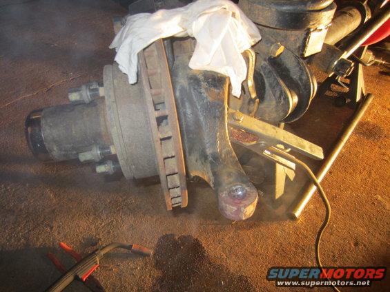 Ford Bronco steering knuckle with brake rotor and hub assembly. A white cloth covers part of the assembly